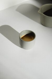 a cup of coffee sitting on a table next to a measuring cup