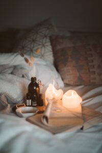 candles and a book on a bed with pillows and blankets